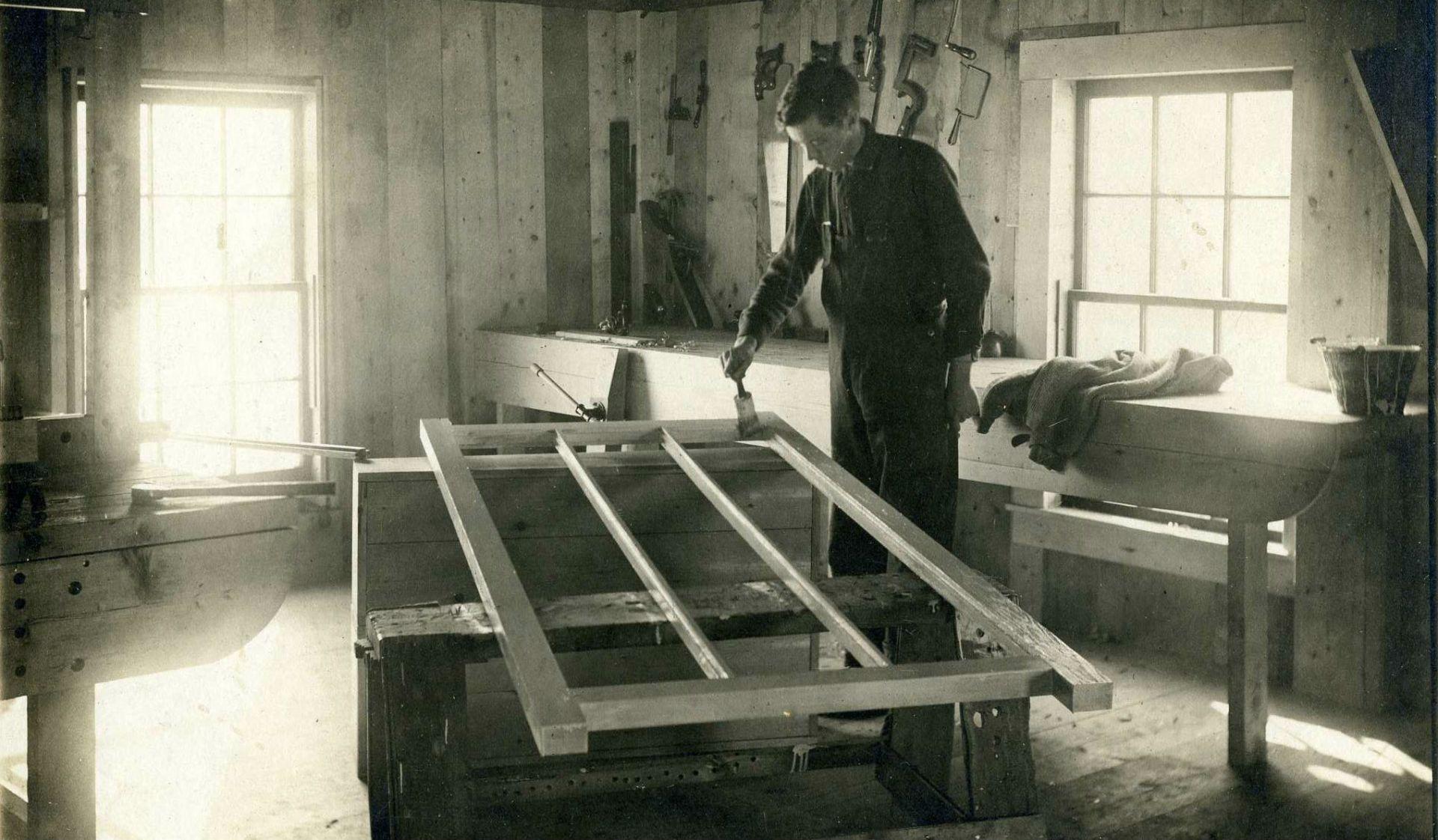 Historic photo of student painting a woodworking project.